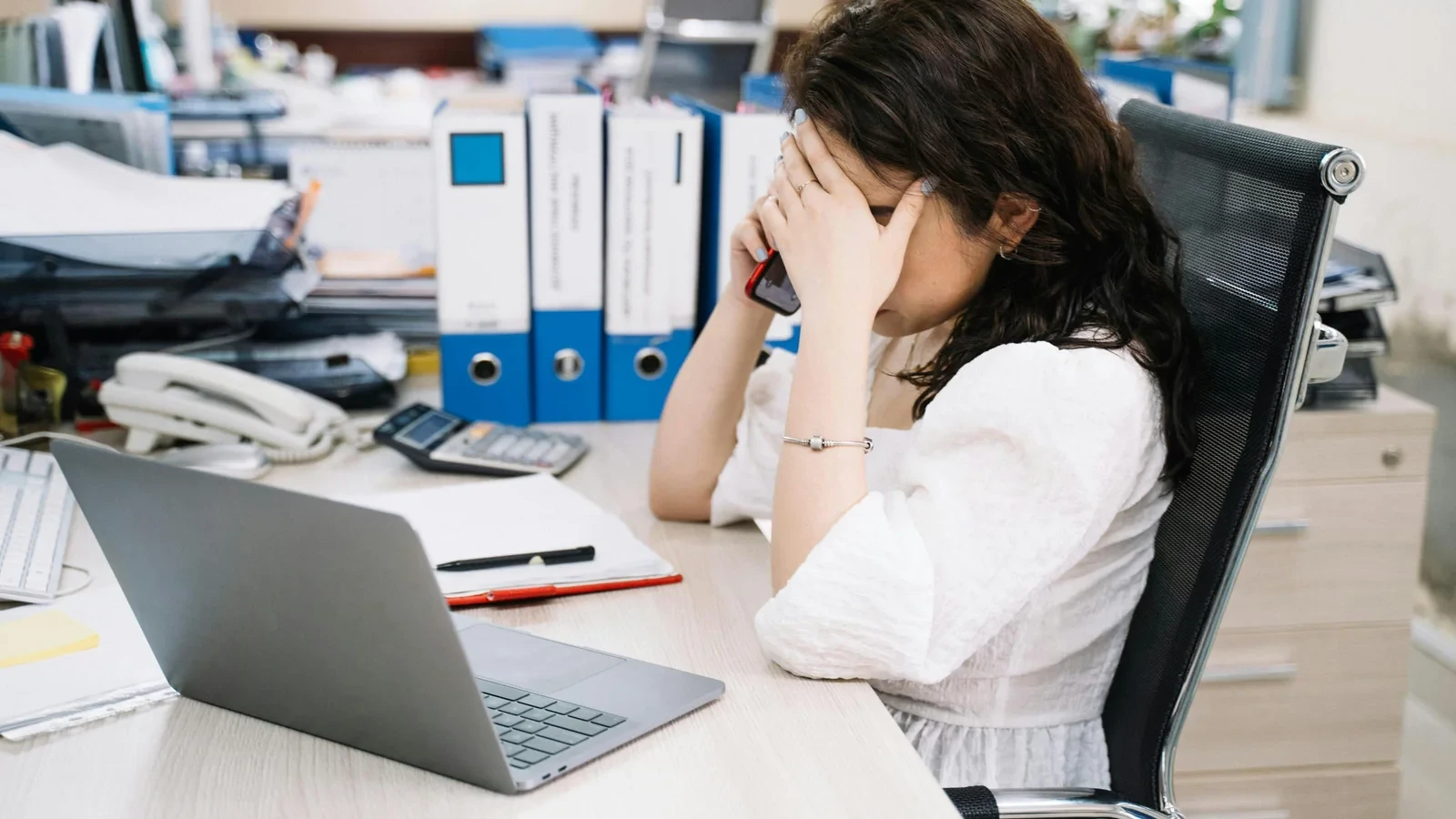 Professionnelle dépassée par ses tâches administratives, assise à son bureau