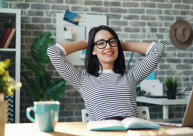 Professionnelle détendue à son bureau, les mains derrière la tête